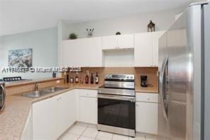 kitchen with sink, stainless steel appliances, white cabinetry, and light tile patterned flooring