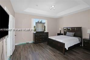 bedroom featuring dark hardwood / wood-style flooring and a raised ceiling