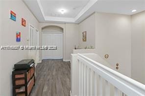 hallway with a raised ceiling and dark hardwood / wood-style flooring