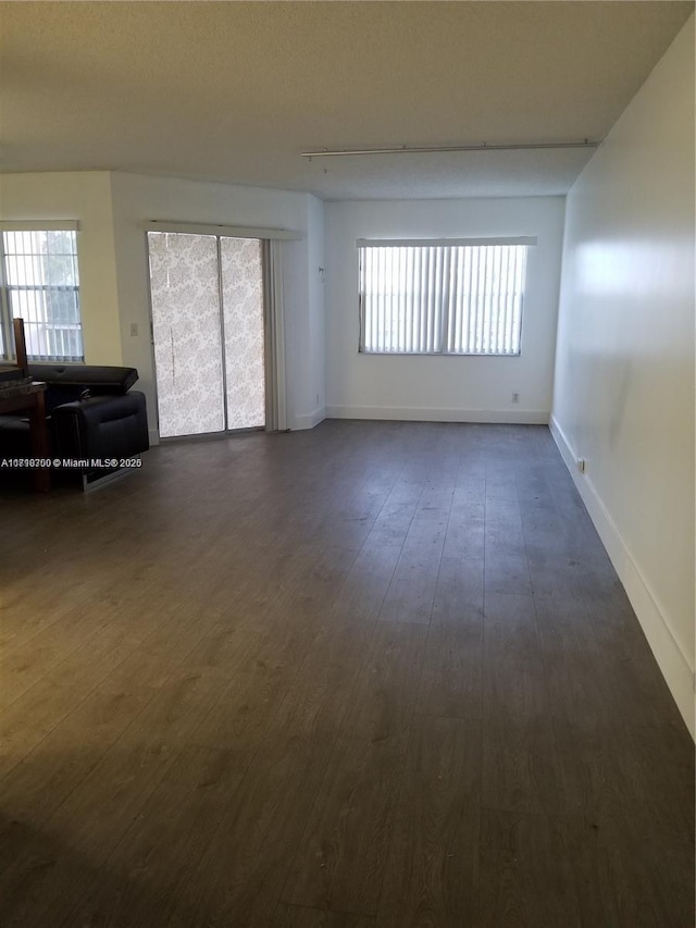 spare room with a healthy amount of sunlight and dark wood-type flooring