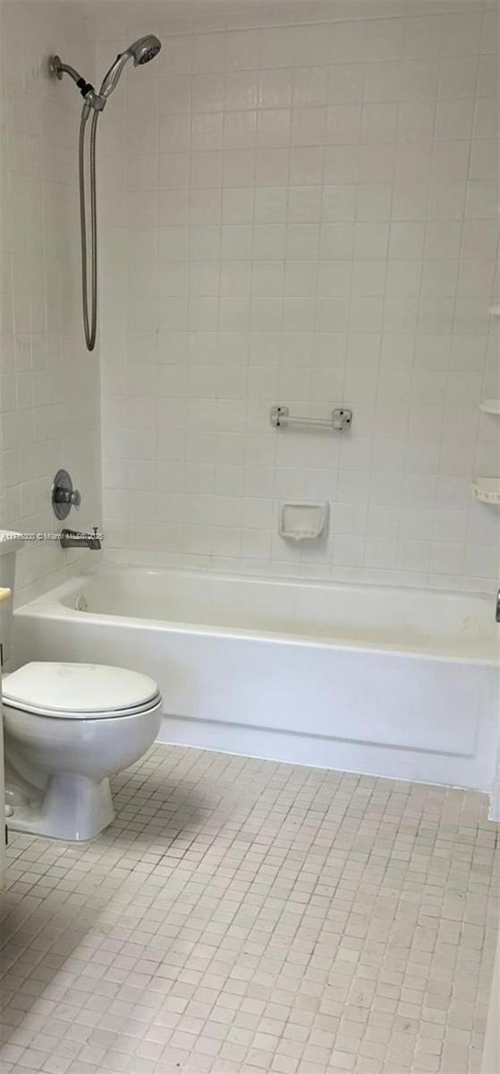 bathroom featuring toilet, tiled shower / bath, and tile patterned floors