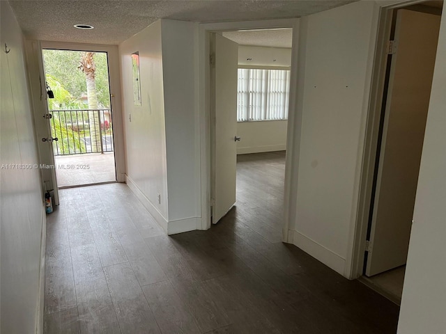 hallway featuring a textured ceiling and dark hardwood / wood-style flooring