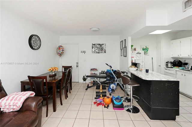 kitchen featuring white cabinets, a textured ceiling, a center island, and light tile patterned flooring