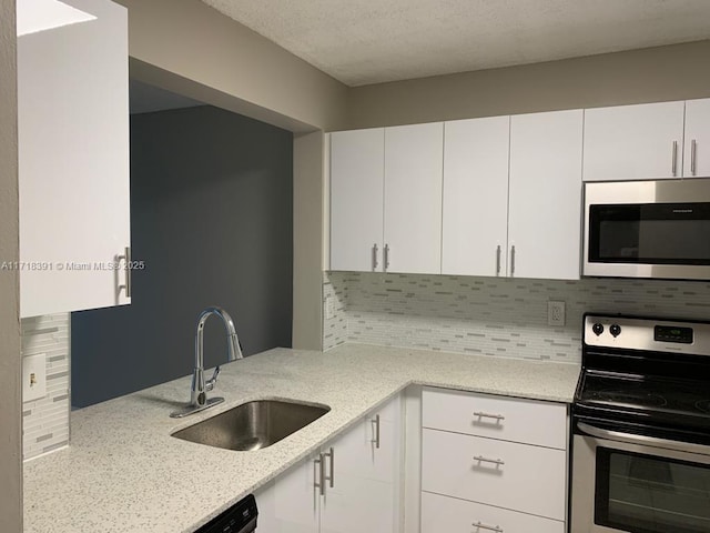 kitchen with backsplash, white cabinetry, sink, and appliances with stainless steel finishes