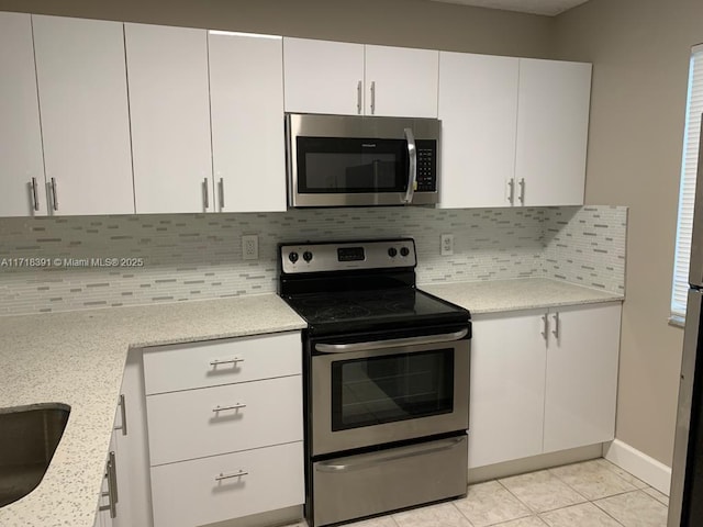 kitchen with decorative backsplash, stainless steel appliances, and white cabinetry