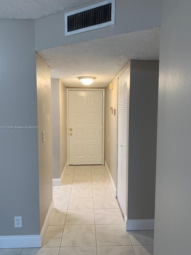 corridor featuring light tile patterned floors and a textured ceiling