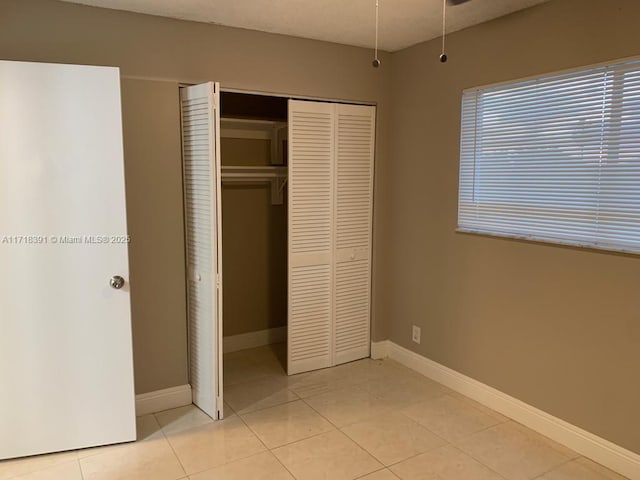 unfurnished bedroom featuring light tile patterned floors and a closet