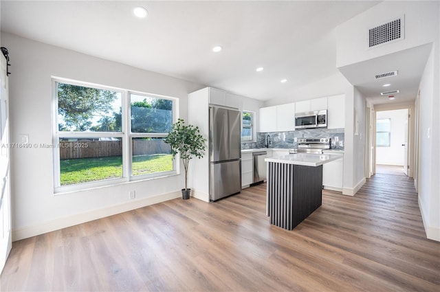 kitchen featuring white cabinets, a kitchen island, stainless steel appliances, and light hardwood / wood-style floors