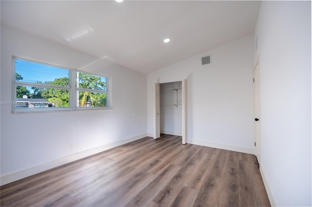 unfurnished bedroom featuring a closet, wood-type flooring, and lofted ceiling