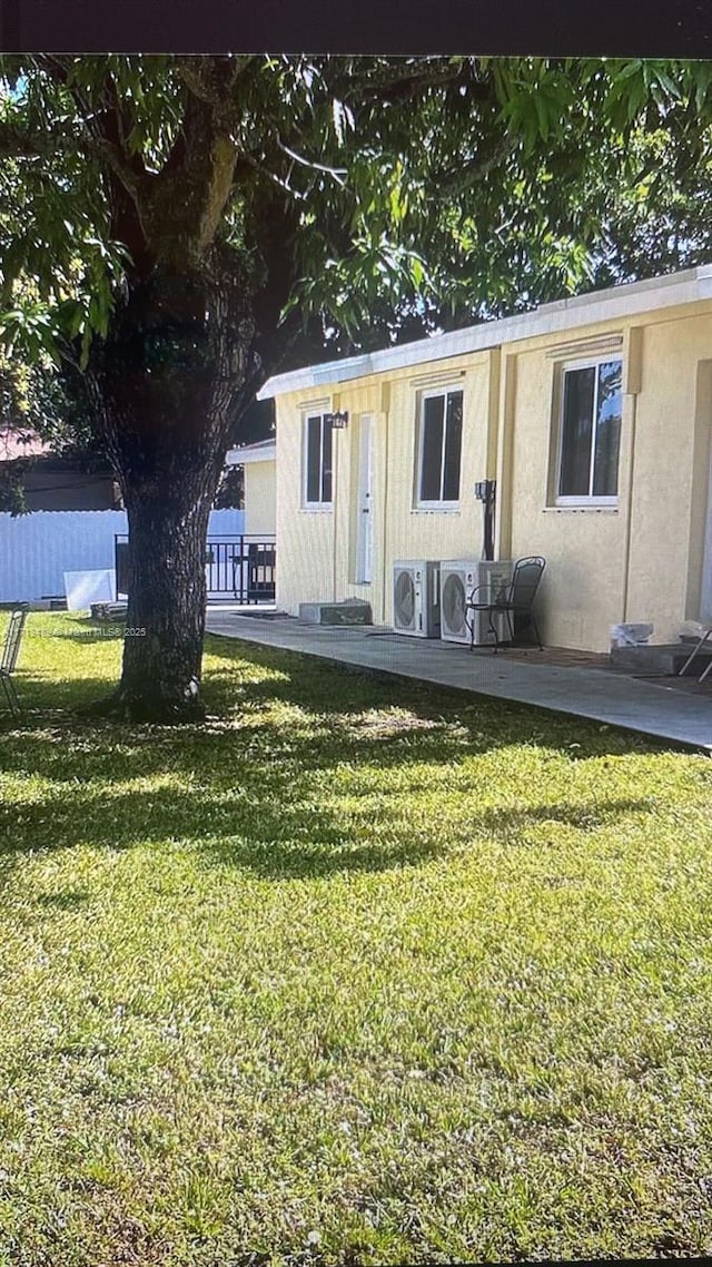 view of front of property with ac unit and a front lawn