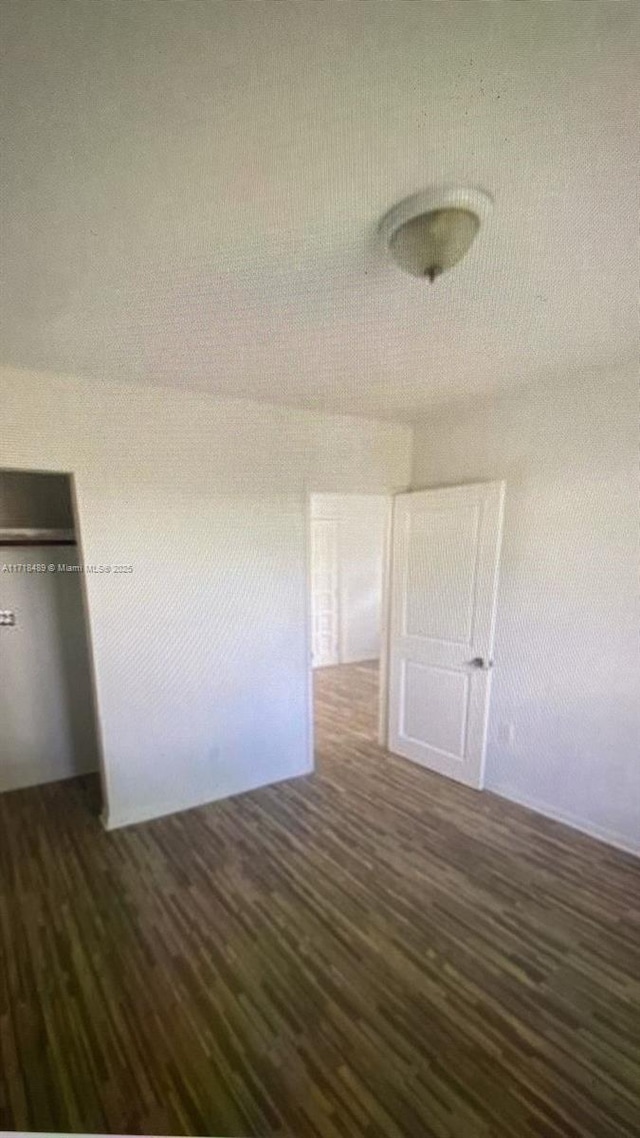 unfurnished bedroom with a closet and dark wood-type flooring