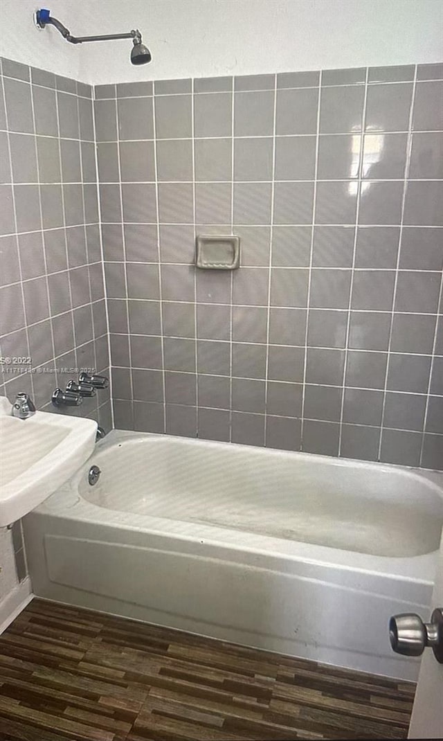 bathroom with hardwood / wood-style flooring and tiled shower / bath