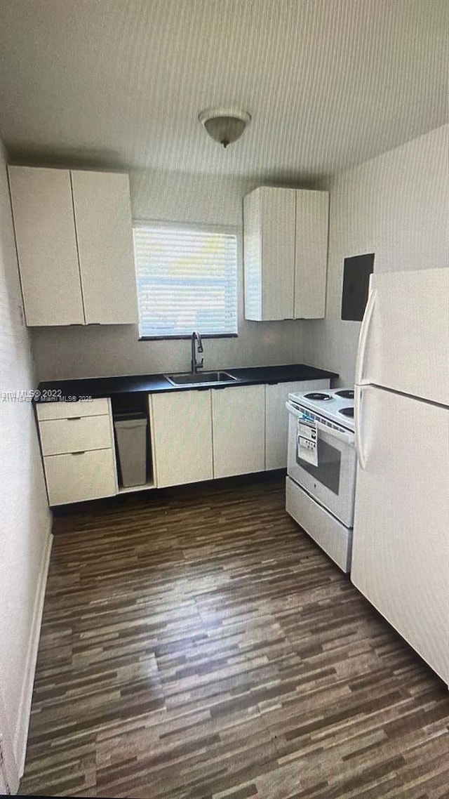 kitchen featuring white appliances, dark wood-type flooring, and sink