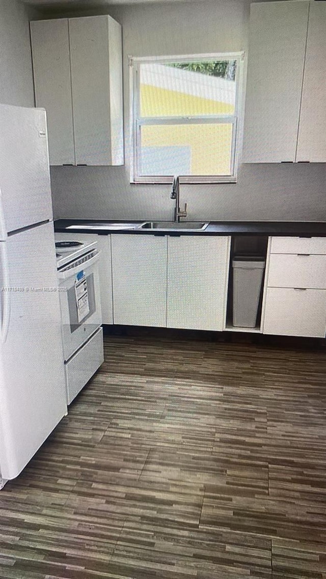 kitchen featuring range, white refrigerator, white cabinetry, and sink