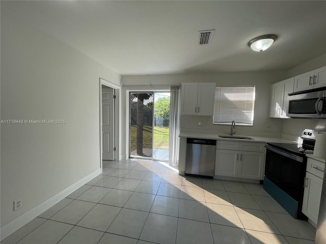 kitchen with light tile patterned floors, stainless steel appliances, white cabinetry, and sink