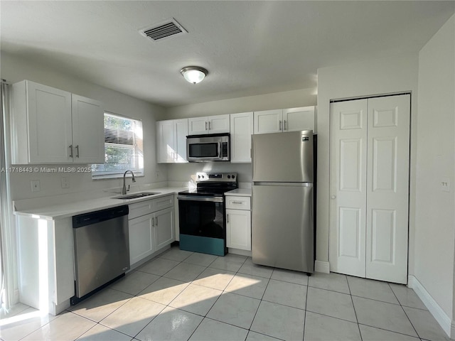 kitchen featuring white cabinets, stainless steel appliances, light tile patterned flooring, and sink