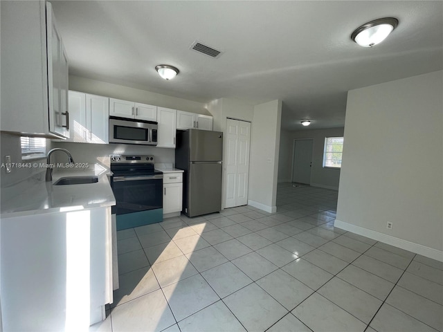 kitchen featuring white cabinets, light tile patterned floors, sink, and appliances with stainless steel finishes