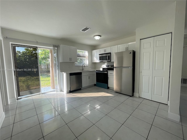 kitchen with white cabinets, light tile patterned floors, sink, and appliances with stainless steel finishes