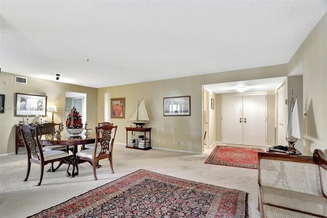 dining space featuring light carpet and a textured ceiling