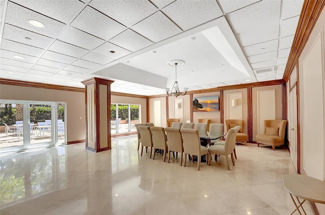 dining area with an inviting chandelier, a drop ceiling, decorative columns, and a wealth of natural light