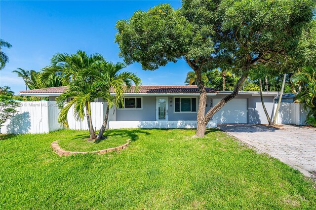 ranch-style house featuring a garage and a front lawn