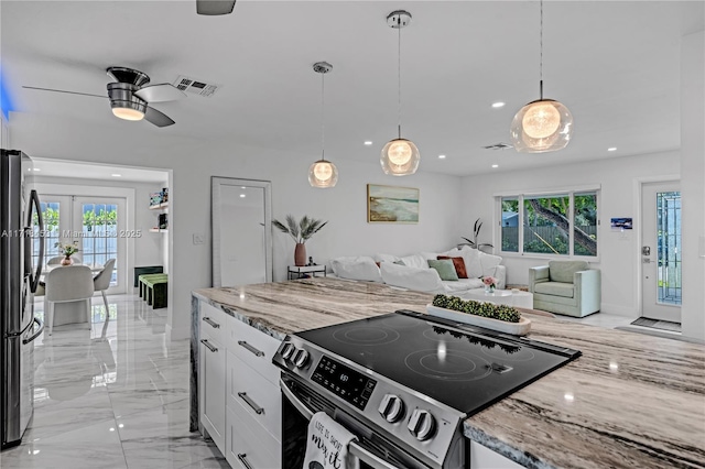 kitchen featuring light stone counters, white cabinets, hanging light fixtures, and appliances with stainless steel finishes