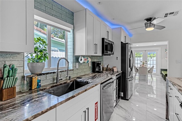 kitchen with stone counters, white cabinets, and appliances with stainless steel finishes