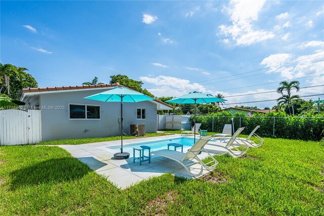 view of swimming pool with cooling unit, a patio area, and a lawn