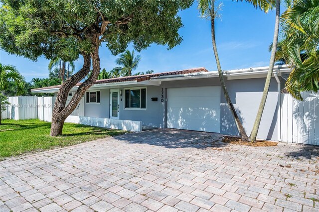 ranch-style home with a garage and a front lawn