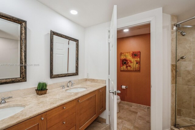 bathroom with vanity, toilet, and tiled shower