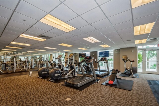 gym with a paneled ceiling and carpet floors