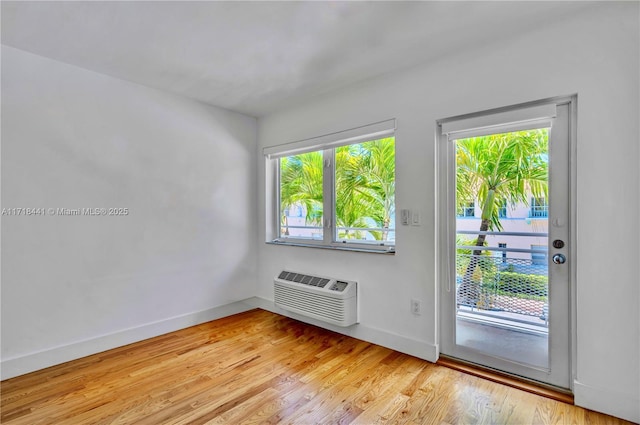 doorway to outside with an AC wall unit and light hardwood / wood-style floors