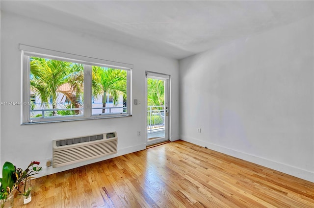 spare room featuring a wall mounted AC and light hardwood / wood-style flooring