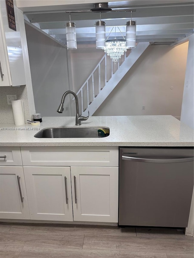 kitchen featuring stainless steel dishwasher, white cabinets, sink, and light hardwood / wood-style flooring