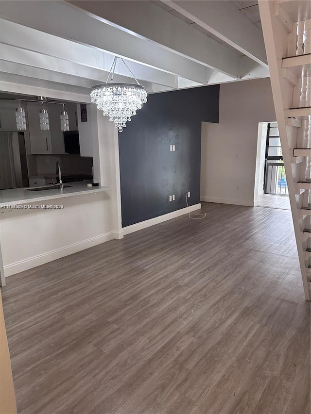 unfurnished living room with a chandelier, beam ceiling, sink, and wood-type flooring