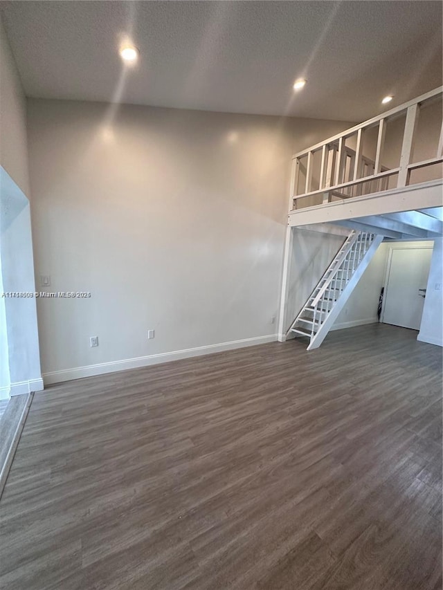 unfurnished living room with a textured ceiling and dark wood-type flooring