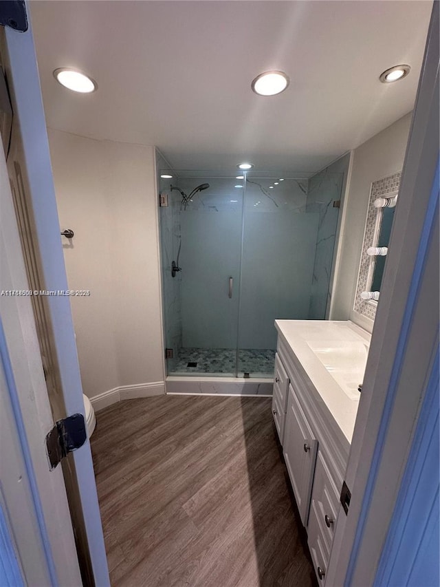 bathroom with toilet, a shower with door, vanity, and hardwood / wood-style flooring