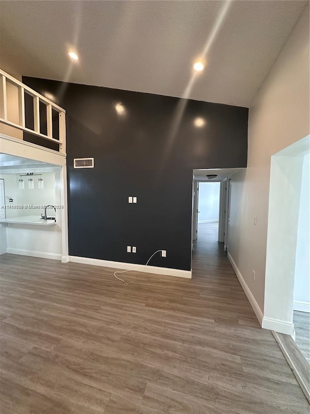 spare room featuring a towering ceiling and hardwood / wood-style flooring