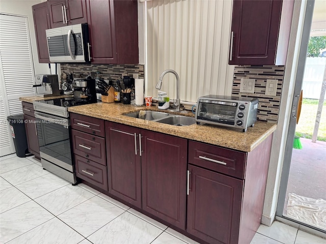 kitchen with light stone countertops, appliances with stainless steel finishes, tasteful backsplash, sink, and light tile patterned floors