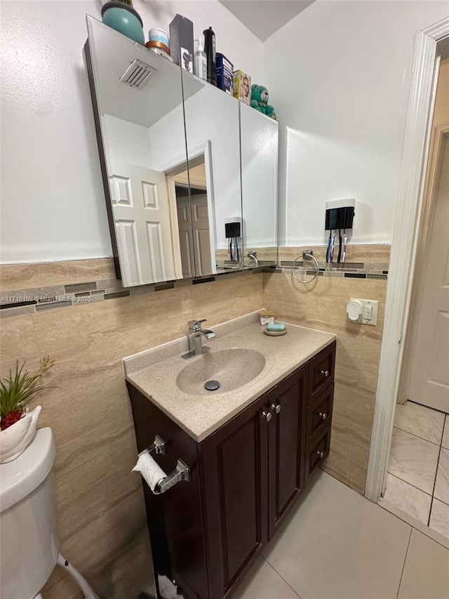 bathroom featuring tile patterned floors, vanity, toilet, and tile walls