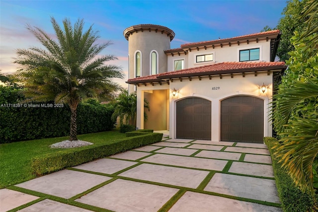 mediterranean / spanish-style home featuring a yard and a garage