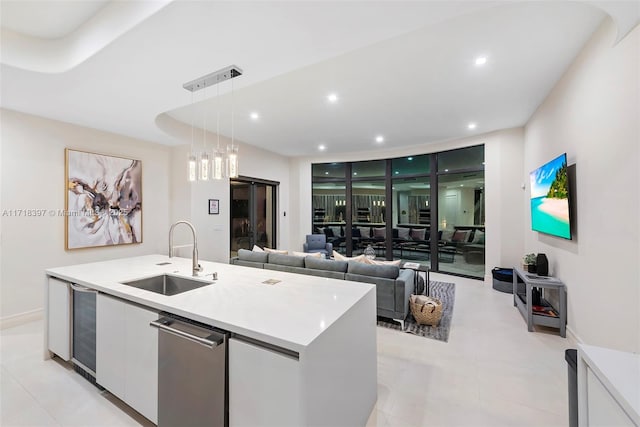 kitchen featuring white cabinetry, sink, hanging light fixtures, beverage cooler, and a kitchen island with sink