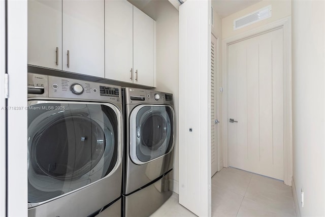 laundry area featuring washer and dryer, cabinets, and light tile patterned flooring