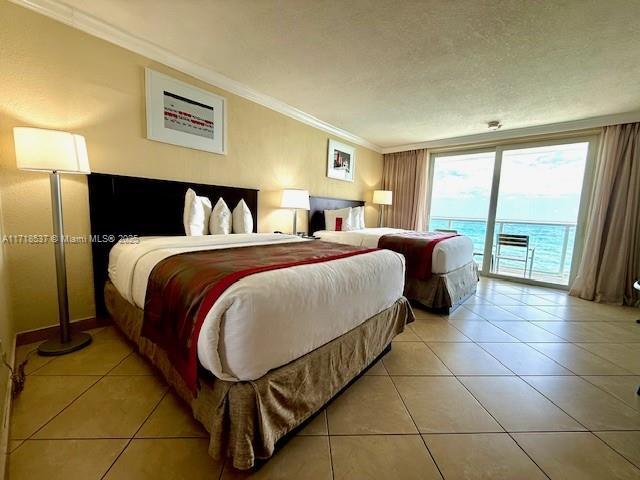 bedroom featuring access to exterior, light tile patterned flooring, crown molding, and a textured ceiling