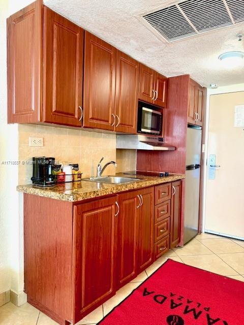 kitchen with visible vents, backsplash, freestanding refrigerator, light tile patterned floors, and built in microwave