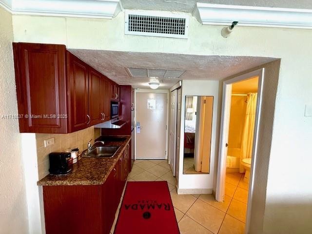 kitchen with decorative backsplash, light tile patterned floors, visible vents, and a sink