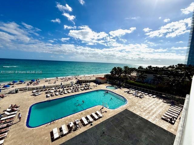 view of pool featuring a water view, a patio, and a beach view