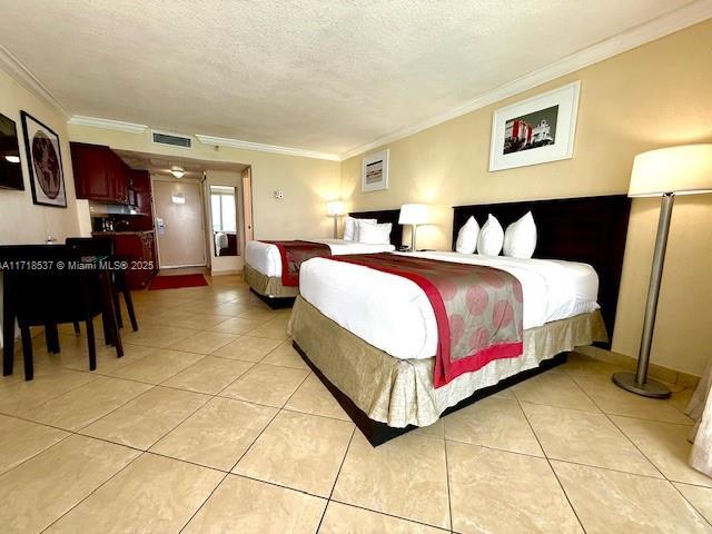 bedroom featuring light tile patterned flooring, visible vents, a textured ceiling, and ornamental molding