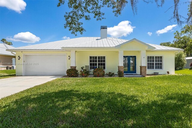 view of front of home with a garage, a front lawn, and french doors