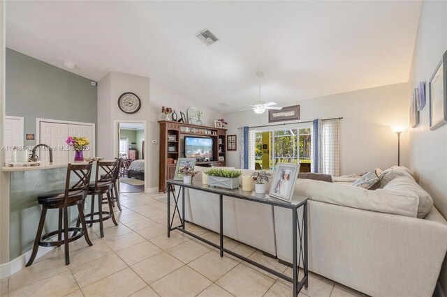 living room featuring lofted ceiling, sink, ceiling fan, and light tile patterned flooring